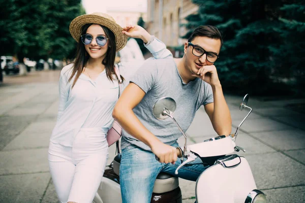 Beautiful young couple sitting on scooter together in the city street — Stock Photo, Image