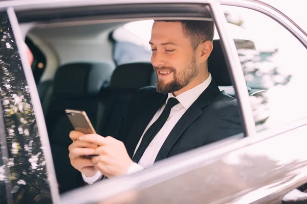 Серйозний бізнесмен, використовуючи телефон у своїй машині, шукає вікно — стокове фото