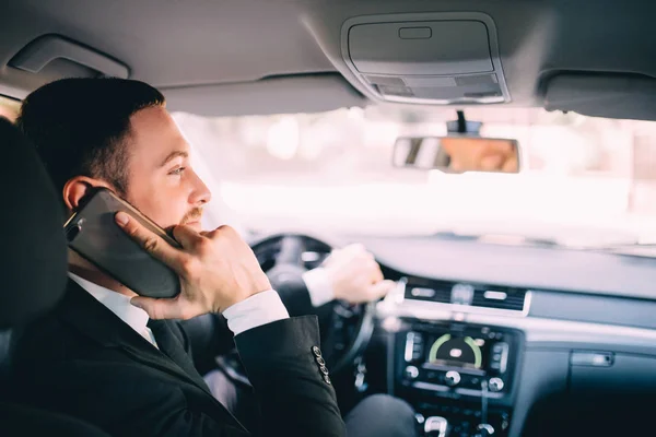 Homem de negócios usando seu telefone enquanto dirige o carro — Fotografia de Stock