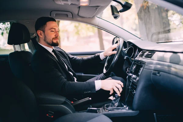 Hombre de negocios guapo en el asiento de los conductores en su coche y cambiar la velocidad — Foto de Stock