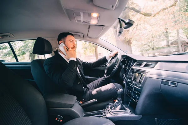 Man using his phone while driving the car. Business man driver speak phone white drive car — Stock Photo, Image