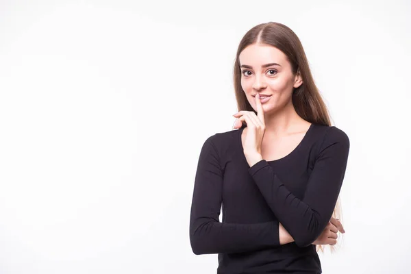 Portrait of funny young Caucasian woman in white shirt and glasses with hair bun holding index finger at lips, asking to keep silence or not tell anyone her secret, raising brows, saying 'shh'. — Stockfoto
