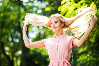 Saçları ile oynarken bir parkta kıvırcık saçlı çekici sarışın kız