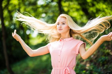 Saçları ile oynarken bir parkta kıvırcık saçlı çekici sarışın kız