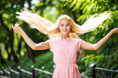 Saçları ile oynarken bir parkta kıvırcık saçlı çekici sarışın kız