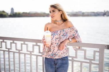 Genç gülümseyen beyaz kadın portresi soğuk limonata dolgu alan arka plan, fincan