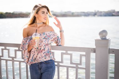 Promenade ve içecek limonata yaz gününde oturan genç çekici kadın portresi