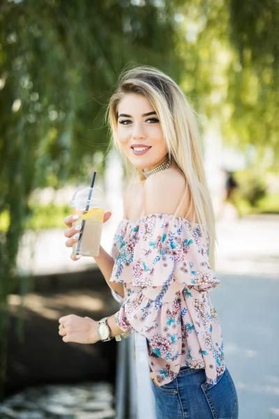 Portakal suyu içme genç mutlu gülümseyen kadın. Güneşli bir gün, açık havada güzel genç kadına yakın çekim.