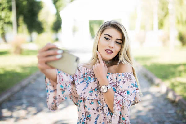 아름 다운 금발 소녀가 공원에서 휴식, 휴대 전화는 selfie. — 스톡 사진