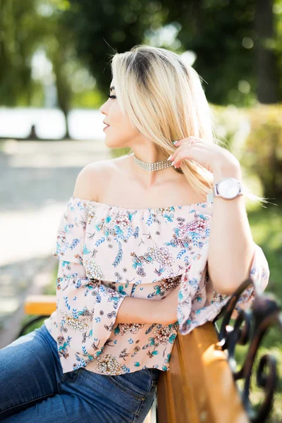 Young woman uses smartphone sitting on bench in the Park. — Stock Photo, Image