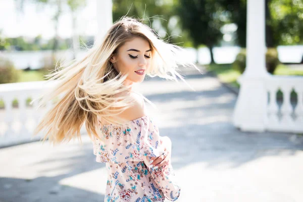 Sokakta yürürken ve gülümseme ile etrafa sallayarak saçlı güzel kız.