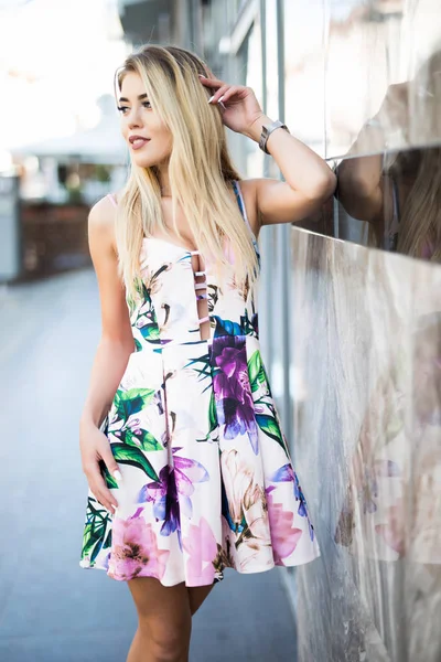 Fiatal gyönyörű lány gyaloglás és épület fal közelében jelentő nyári ruha — Stock Fotó