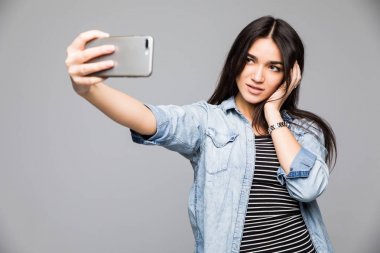 Gülümseyen genç kız selfie fotoğraf smartphone üzerinde gri arka plan yapma.