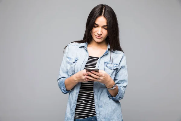 Retrato de uma menina feliz usando smartphone isolado em um fundo cinza — Fotografia de Stock