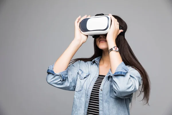 Sonríe mujer feliz obtener experiencia usando gafas VR-auriculares de realidad virtual sobre fondo gris — Foto de Stock