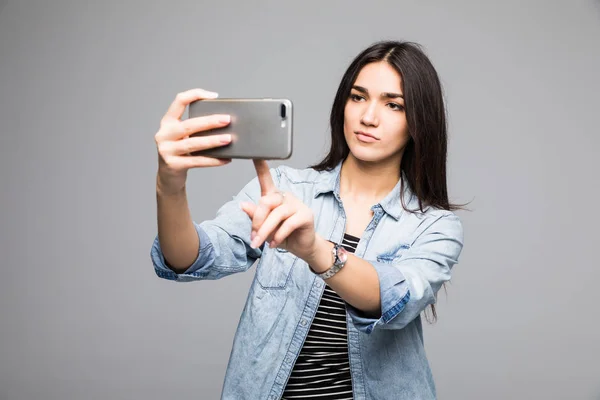 Красивая девушка прижимает палец к сенсорному телефону, изолированному на сером фоне — стоковое фото