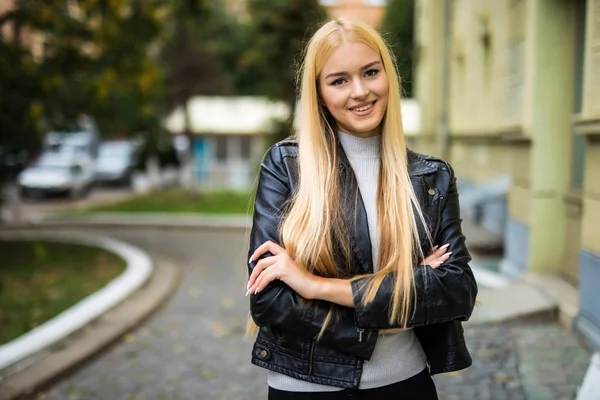 Feliz chica bonita de pie con los brazos cruzados al aire libre con una vista de la ciudad — Foto de Stock