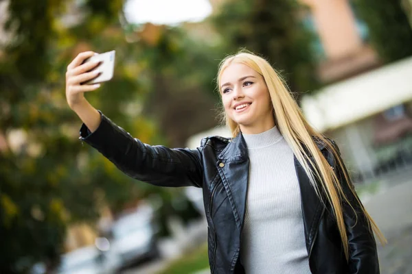 Porträt einer jungen schönen Studentin Videoanruf, Selfie, ein Telefon in der Hand. — Stockfoto