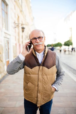 İyi haber paylaşımı. Mobil telefonda konuşurken ve şehir sokak gülümseyen kıdemli yakışıklı.