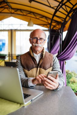 Üst düzey adam akıllı telefon ve kafede dizüstü