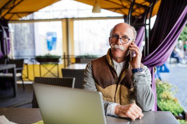 Üst düzey adam akıllı telefon ve kafede dizüstü