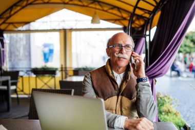 Üst düzey adam akıllı telefon ve kafede dizüstü