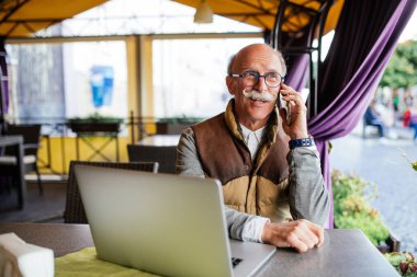 Üst düzey adam akıllı telefon ve kafede dizüstü