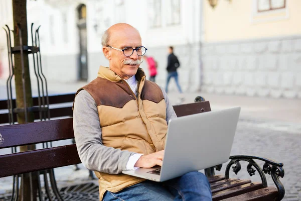Sokakta tezgah üzerinde dizüstü bilgisayar kullanan üst düzey yakışıklı adam