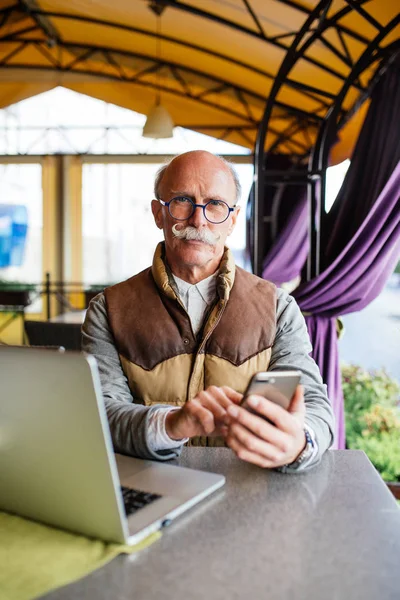 Üst düzey adam akıllı telefon ve kafede dizüstü