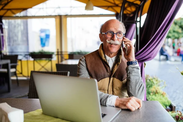 Üst düzey adam akıllı telefon ve kafede dizüstü