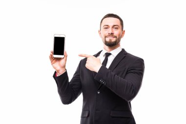 Takım elbiseli genç iş adamı ekran kopya alanı üzerinde cep telefonunu işaret etti. Tam vücut uzunluğu portre studio beyaz arka plan üzerinde izole.