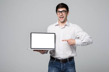 Boş ekran dizüstü gri arka plan üzerinde gösterilen yakışıklı genç işadamı