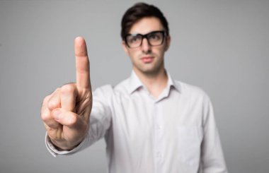 Gri arka plan üzerinde beyaz gömlek giymiş adam işaret parmağı jest