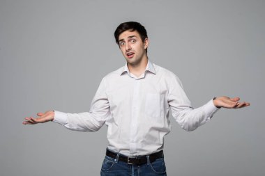 İki ürün gri arka plan üzerinde izole bir denge gösterilen gömlek gülümseyen genç adam.