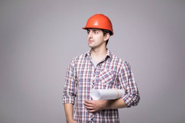 Yakışıklı genç mimar koruyucu kask içinde gri arka plan üzerinde taslak ders çalışıyor