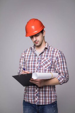 Yakışıklı erkek tarafına bakarak ve gri siyah klasörde tutarak bir siyah takım elbise ve inşaat kask içinde