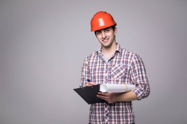 Yakışıklı erkek tarafına bakarak ve gri siyah klasörde tutarak bir siyah takım elbise ve inşaat kask içinde