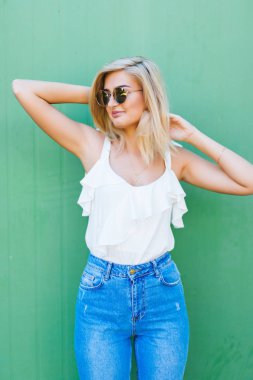 Eğlenceli ve renkli. Yeşil duvara poz şortlu genç oldukça mutlu kadın.