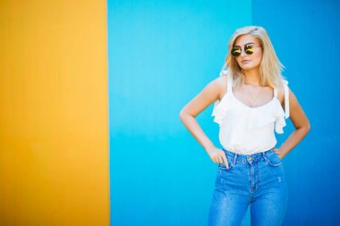 Genç ve güzel kadın sarışın stiliyle renkli duvara karşı.
