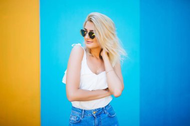 Genç ve güzel kadın sarışın stiliyle renkli duvara karşı.