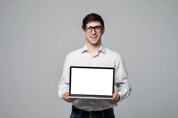 Homme d'affaires souriant pointant du doigt sur écran d'ordinateur portable vierge sur fond gris . — Photo