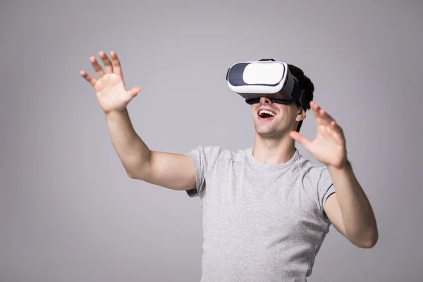 Närbild porträtt av stilig hane i grå t-shirt, uppleva virtuell verklighet med hjälp av Vr headset glasögon. Ung man bär skyddsglasögon, spelar TV-spel mot grå vägg — Stockfoto