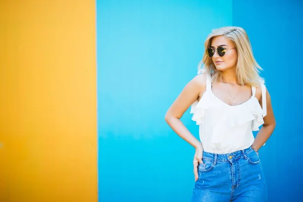 Genç ve güzel kadın sarışın stiliyle renkli duvara karşı. — Stok fotoğraf