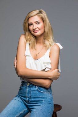 Güzel kadın moda stil geri gri izole sandalyede oturan poz.