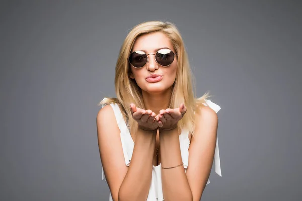 Carino donna che soffia bacio a macchina fotografica su sfondo grigio — Foto Stock