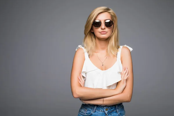 Jeune femme séduisante en jeans et lunettes de soleil posant en studio sur fond gris non isolé, fille blonde hipster concept de tenue d'été, photo avec place pour le texte — Photo