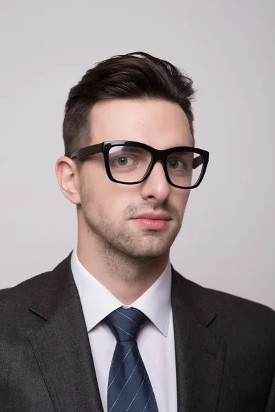 Retrato de um homem de negócios jovem e de moda com óculos nerd em cinza — Fotografia de Stock