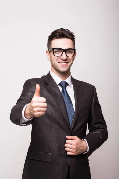 Hombre de negocios sonriente con pulgar hacia arriba sobre fondo gris — Foto de Stock