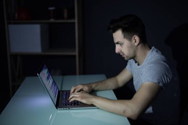 Karanlık ofisinde beyaz masa masaüstü bilgisayarda çalışan erkek programcı