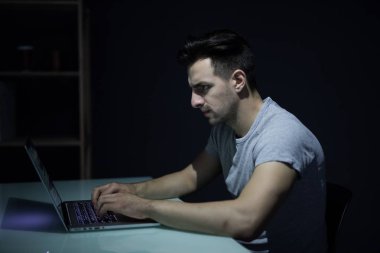 Karanlık ofisinde beyaz masa masaüstü bilgisayarda çalışan erkek programcı
